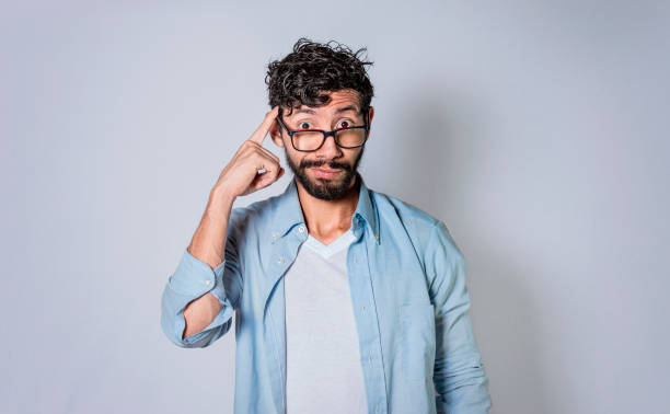 istock young man wondering with his finger on isolated background, A guy thinking with his finger on his head. 1369499620