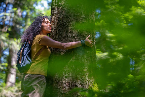 istock Side view of a mature woman embracing a tree in forest 1369500643