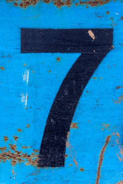 istock Number 7 in black paint on an old blue iron surface with rust texture and traces of dirt. 1369501513