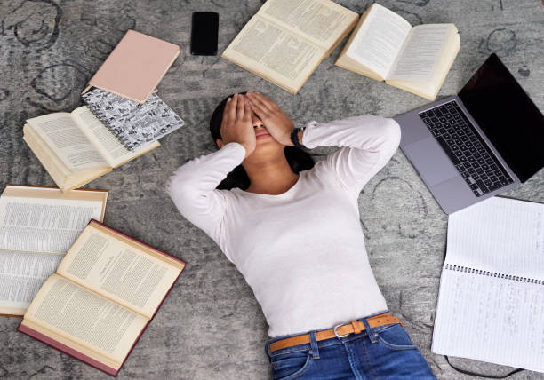 tiro de ângulo alto de uma jovem estudante irreconhecível olhando estressado enquanto estudava na biblioteca - nerd student female exam - fotografias e filmes do acervo