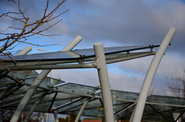 fahrradabstellraum mit glasdach mit gepunktetem aufdruck. konstruktion aus gebogenen grauen rohren in einen lichtbogen. gehärtetes verbundglas, das an metallgriffen in einem stadtpark befestigt ist. - x stand stock-fotos und bilder