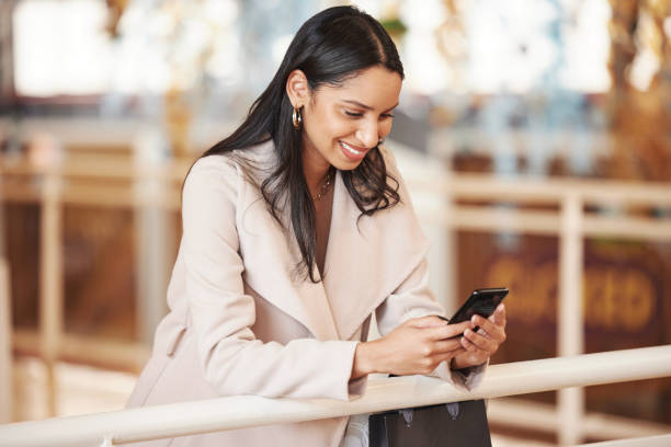 istock Shot of a young woman using her smartphone to send a text while shopping 1369505847