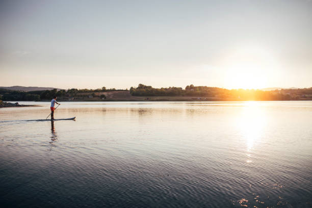 istock Man floating on the lake on paddle board 1369507279