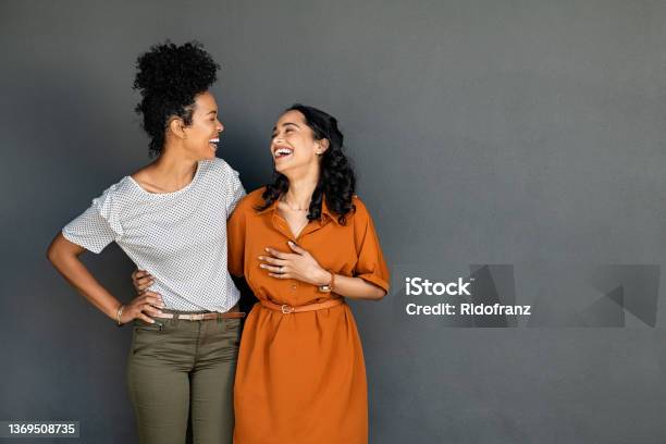 Two Women Friends Embracing And Laughing On Grey Background Stock Photo - Download Image Now