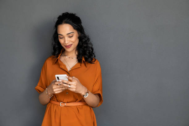 istock Mixed race young woman using smartphone isolated on grey wall 1369508923