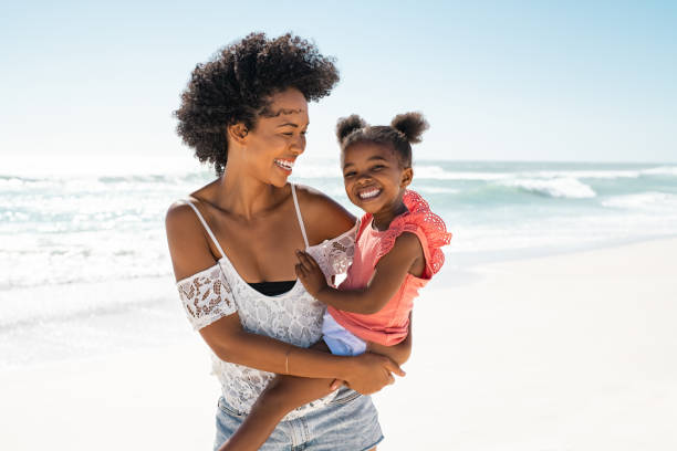 istock Happy black young mother carrying daughter at beach 1369509331