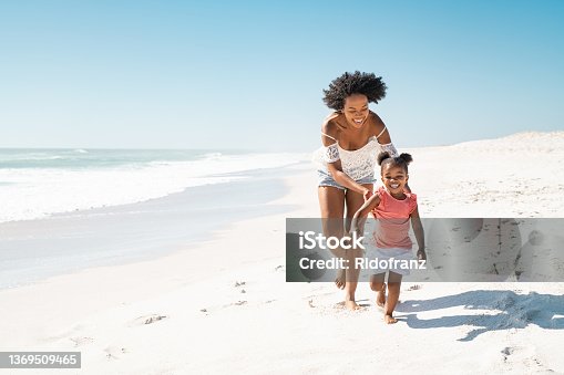 istock African mother running after her daughter on the beach 1369509465