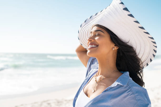 istock Latin woman relaxing on beach with white straw hat 1369509503