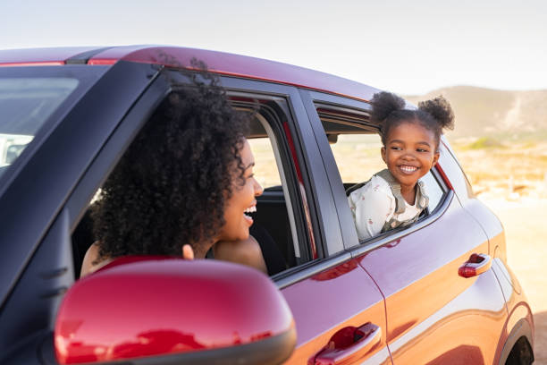 Mother and black daughter peeping outside car Cheerful little african american daughter sitting on back seat of car looking at mother from mirror while travelling. Young woman with cheerful female kid enjoying road trip. Fun woman with daughter traveling in car while looking at each other. back seat photos stock pictures, royalty-free photos & images