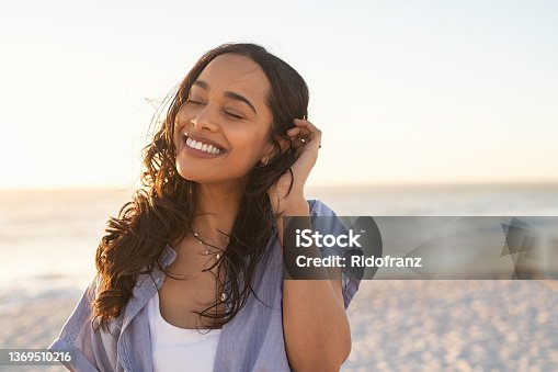 istock Carefree beautiful latin woman relaxing on beach 1369510216