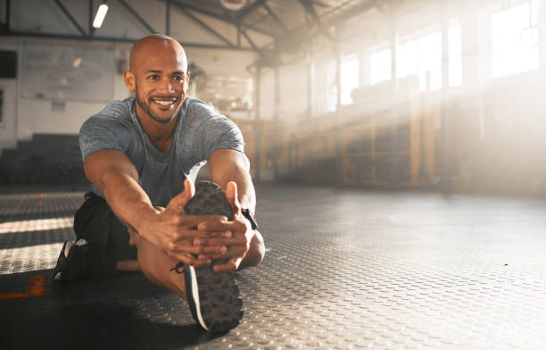 Shot of a young man stretching his legs before a workout