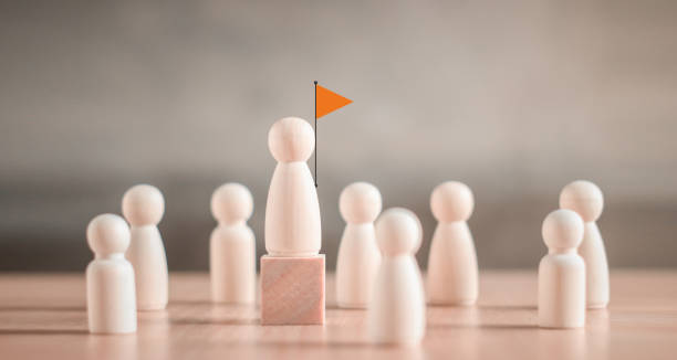 Wooden figure standing on a cube higher than others - concept of leadership or hierarchy stock photo