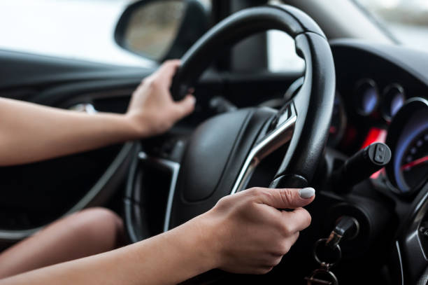 istock Women's hands on the steering wheel, inside the car. 1369513761
