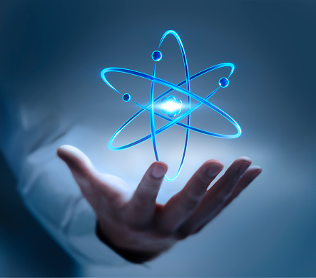 Hand  showing atom nucleus and electrons symbol on dark blue background
