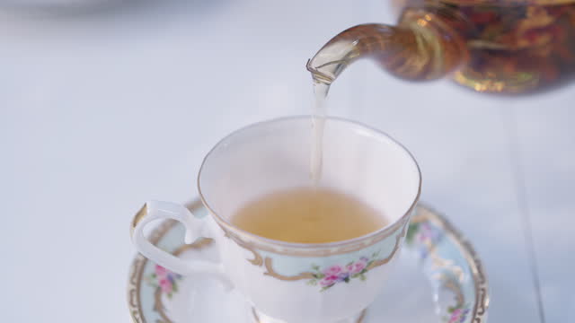 High angle view of pouring flower tea from transparent teapot