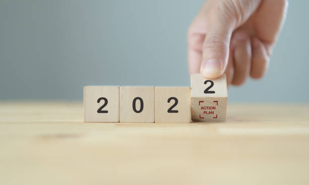 istock Action plan in 2022 concept  for business strategy and development. Hand flips wooden cubes 