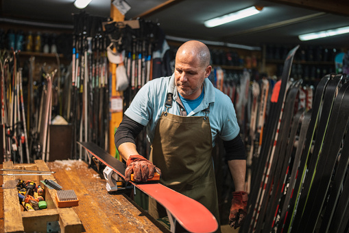 Man in ski retail and repair shop working on a pair of ski.