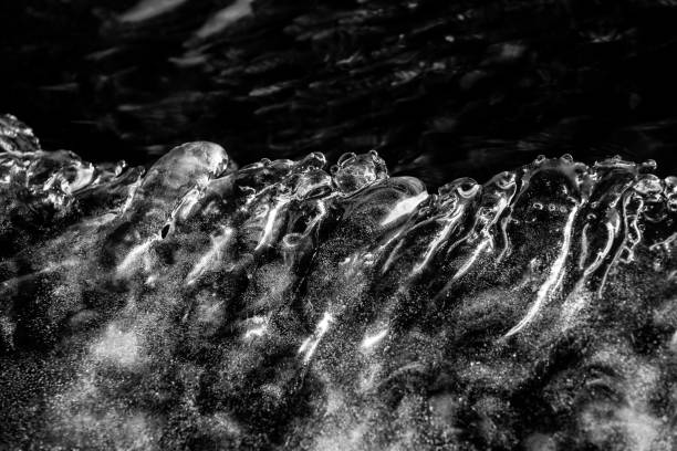 Climate change leads to global natural disasters, abnormal temperatures, heavy snowfalls, typhoons and droughts. Abstract view through large icicles hanging from a winter roof. Black and white.