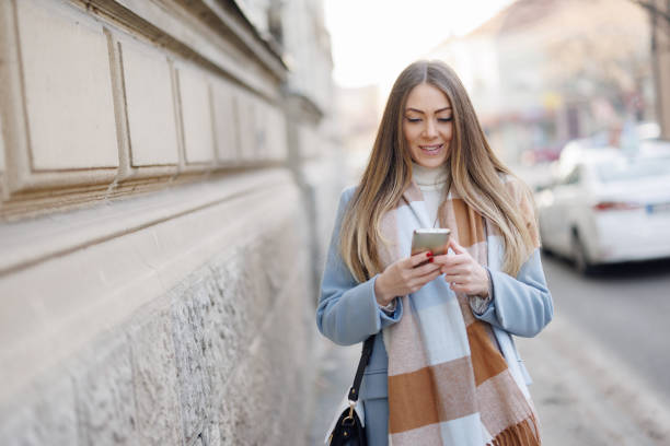 istock Confident young woman using mobile phone on the street 1369520884