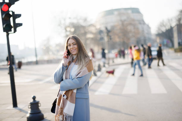 istock Confident young woman using phone in the city 1369521199