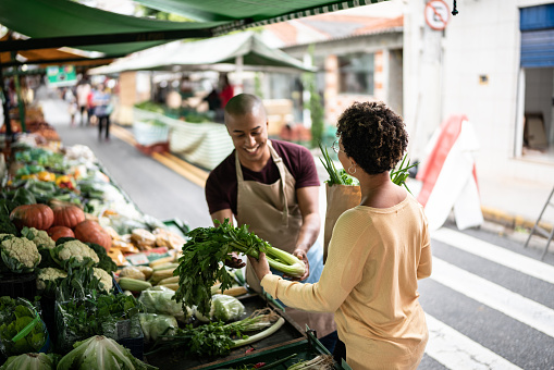 Market seller showing the vegetables to customer