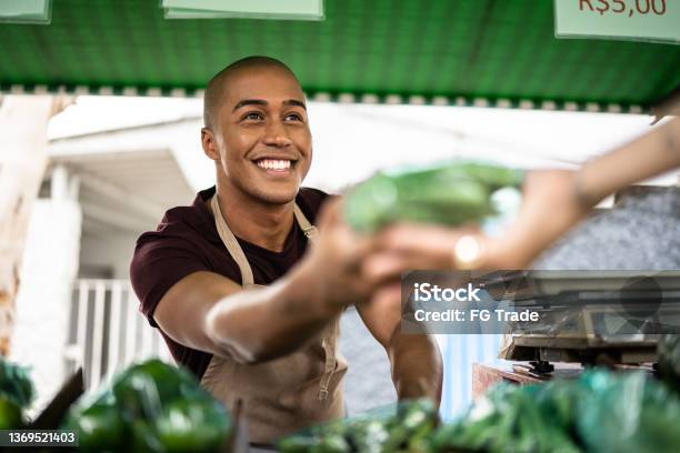 Seller Handing A Vegetable To A Customer At A Street Market Stock Photo - Download Image Now