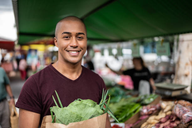 porträt eines jungen mannes auf einem straßenmarkt - shaved head stock-fotos und bilder