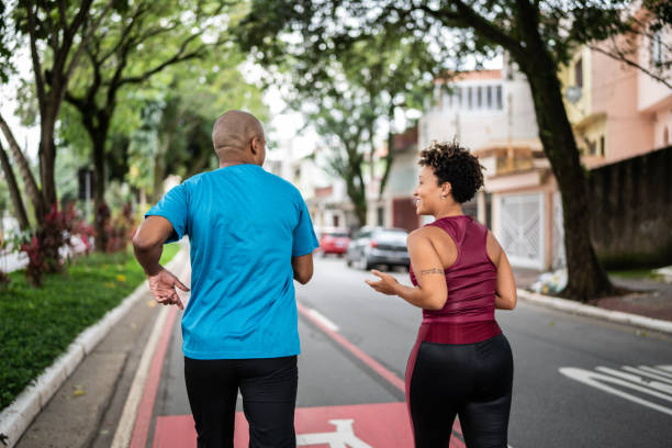 junges paar joggen im straße - road running stock-fotos und bilder