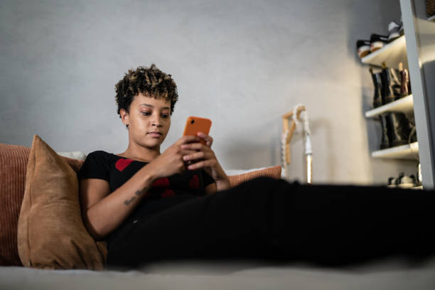 istock Young woman using the mobile phone in the bed at home 1369522450