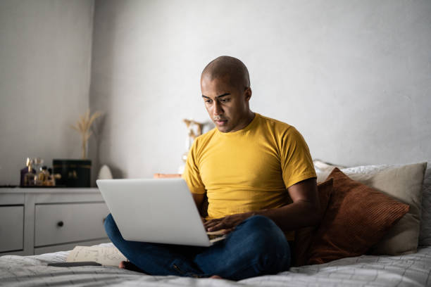 istock Young man using the laptop in the bed at home 1369522562