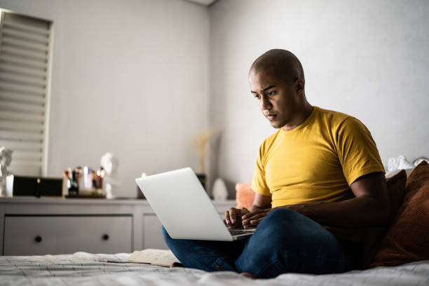 istock Young man using the laptop in the bed at home 1369522565