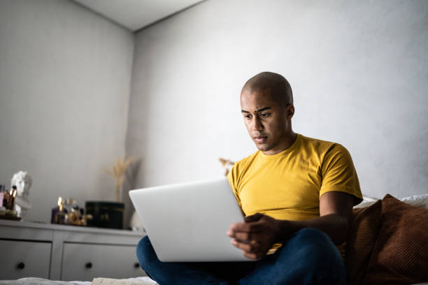 istock Young man using the laptop in the bed at home 1369522566