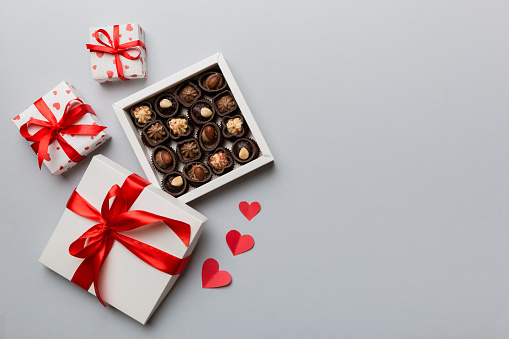 Delicious chocolate pralines in red box for Valentine's Day. Heart shaped box of chocolates top view with copy space.