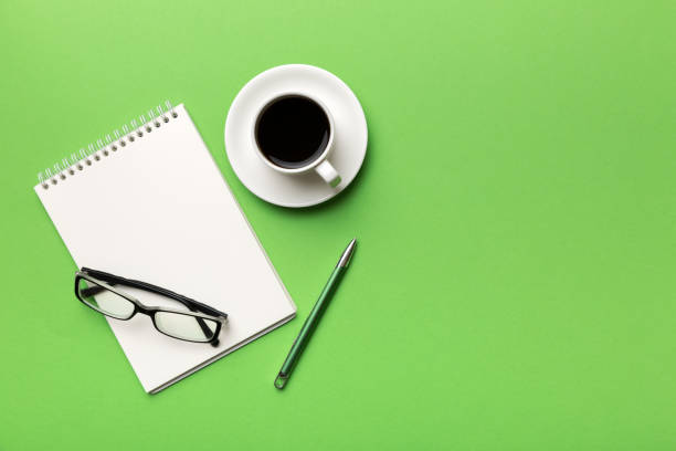 istock Modern office desk table with notebook and other supplies with cup of coffee. Blank notebook page for you design. Top view, flat lay 1369522803