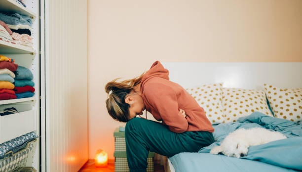 woman with stomach pain staying home - indigestie fotos stockfoto's en -beelden
