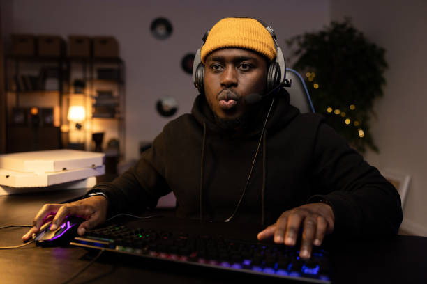 istock A focused guy in a yellow cap with a headset is playing a video shooter carefully on a computer. Online multiplayer championship. In the background a dark room at night with a mess of pizza boxes 1369525226