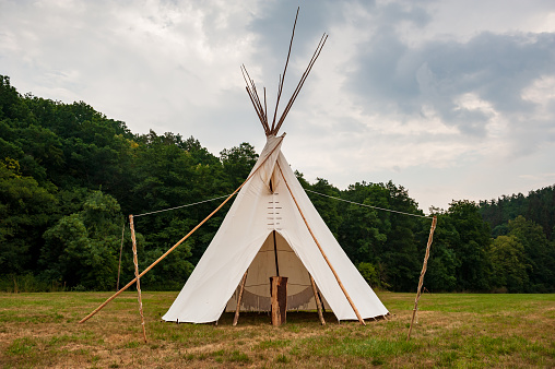 Beautiful view of the summer wedding tipi in a field. Tee pee built on green grass. Traditional teepee tent wigwam located in nature.