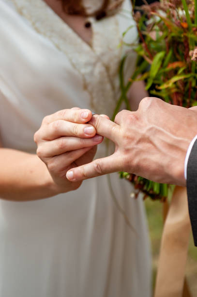 istock Young bride put wedding ring on the groom's finger with difficulties, close-up. Wedding ceremony, hardly exchanging. Future husband wearing a wedding ring. Swollen finger. 1369525388