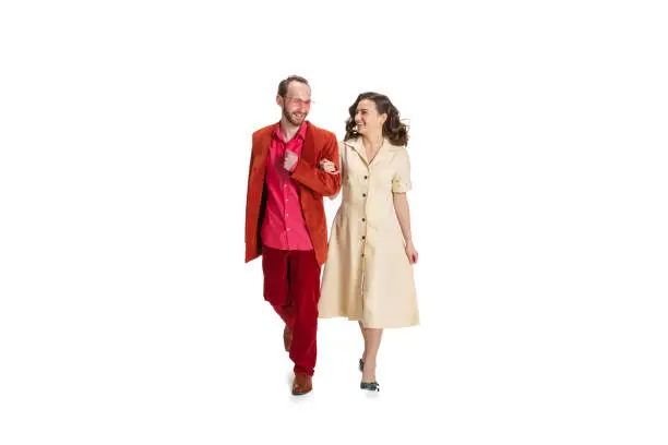 Photo of Young married couple, young man and woman in old-school fashioned attire strolling isolated on white background. Vintage, hipster