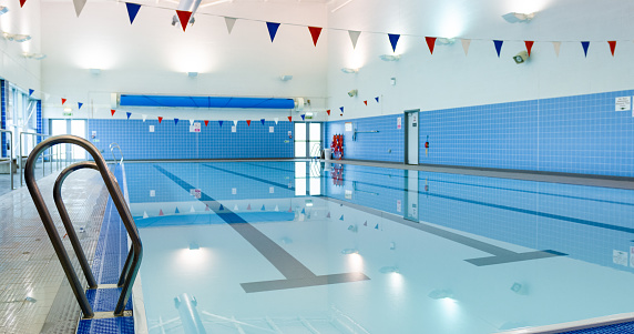 An empty swimming pool in Boldon, North East England. There is bunting hanging over the pool.