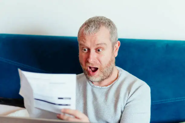 Photo of Worried man checking bills at home