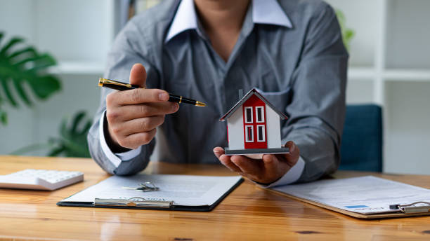 A mortgage broker holding a miniature house