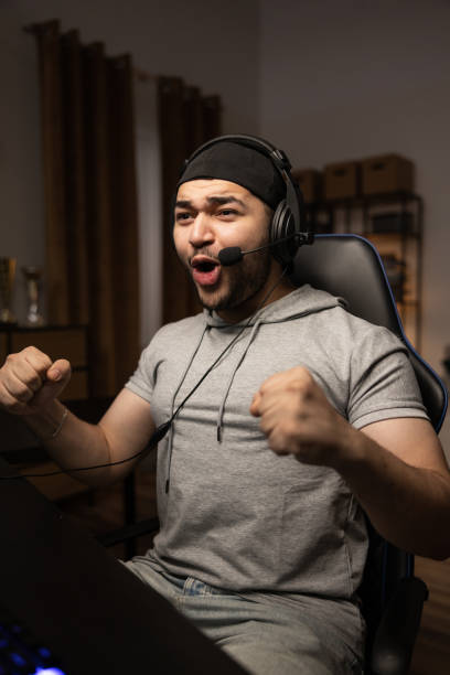 istock A professional player with a headset playing and winning a video game on his computer. Online championship in a virtual world. Clenched fists with joy at the victory shout 1369529735