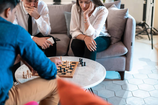 istock Multiethnic group of business people playing chess while having a break in relaxation area at modern startup office 1369531351