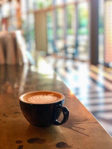 A flat white sits on the counter of a brightly lit East London coffee shop