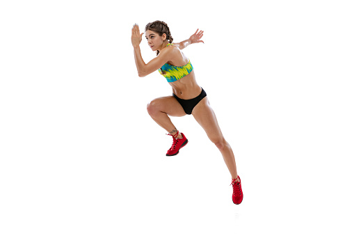 Dynamic portrait of professional female runner, athlete in summer sports uniform training isolated on white background. Muscular, sportive girl. Concept of action, motion, youth, healthy lifestyle.
