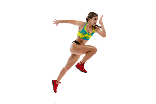 Studio shot of professional female runner, athlete in summer sports uniform training isolated on white background. Muscular, sportive woman. Concept of action, motion, youth, healthy lifestyle.