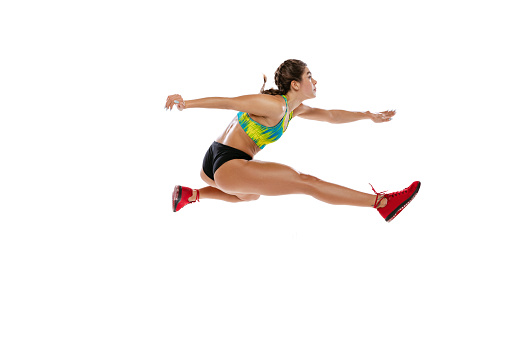 Sport of racing over hurdles. Professional female runner, athlete jumping, running isolated on white background. Muscular, sportive girl. Concept of action, motion, youth, healthy lifestyle.