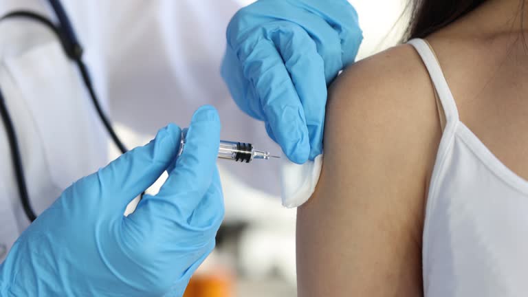 Doctor in gloves holds syringe with vaccine and injects patient in shoulde