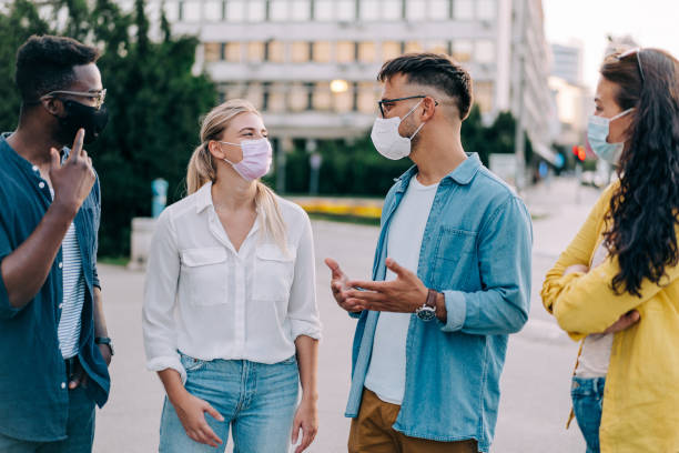 istock Friends with protective face masks talking outdoors in the city. 1369536903